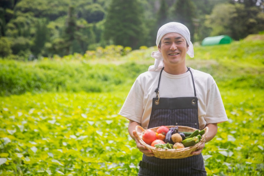 収穫した野菜を持つ生産者